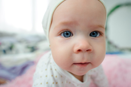 A photograph of a baby who is almost touching the camera's lens. Wide angle portrait