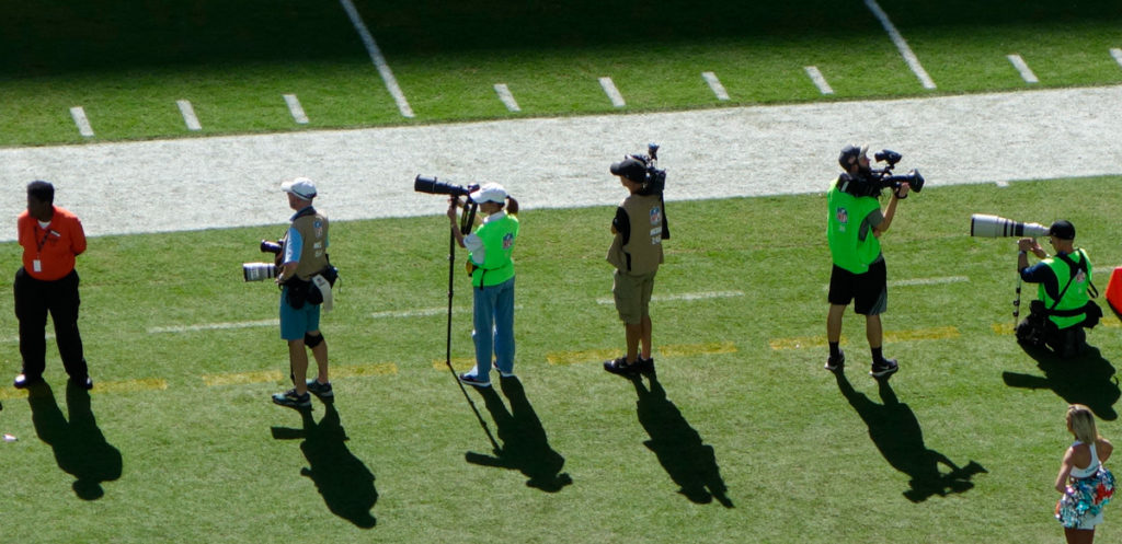 photographers on the sideline at an american football game