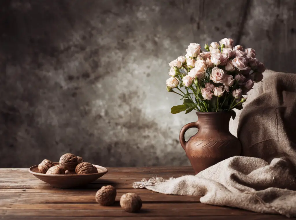 Still life composition with vase, textured background and wooden table