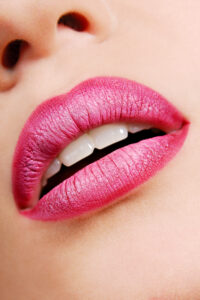 Beauty shot of a closeup of a woman's lips with pink lipstick, and smooth skin. 